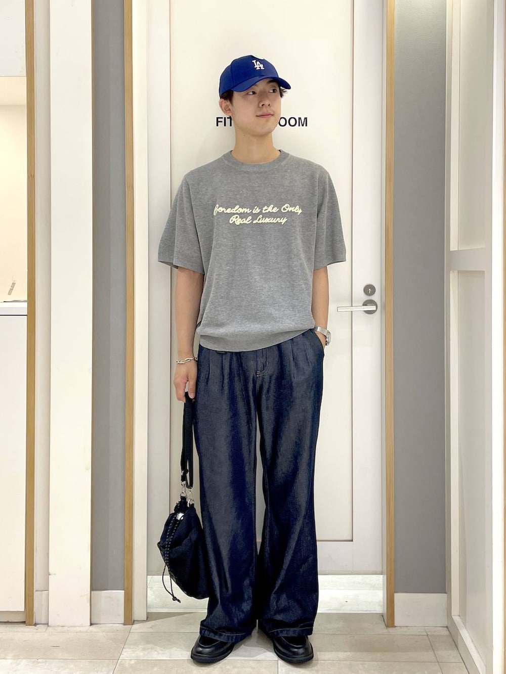 ブラック系のショルダーバッグ、グレー系のニット/セーター、ブルー系のデニムパンツを着用したメンズの夏コーディネートの4枚目の写真