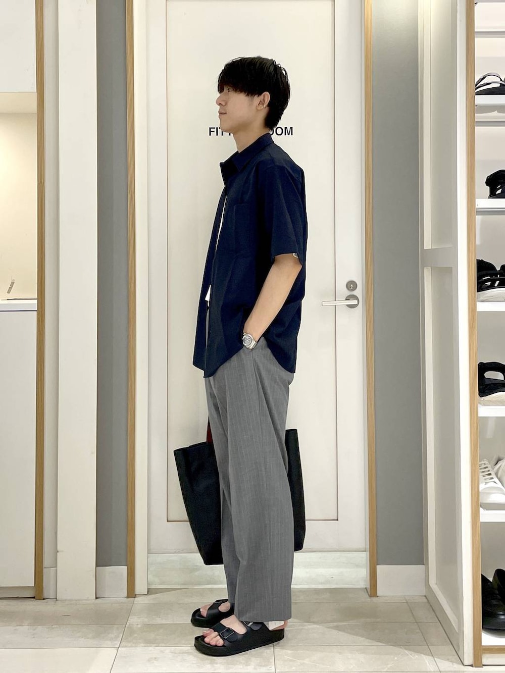 ブラック系のトートバッグ、グレー系のスラックス、ホワイト系のTシャツ/カットソーを着用したメンズの夏コーディネートの4枚目の写真