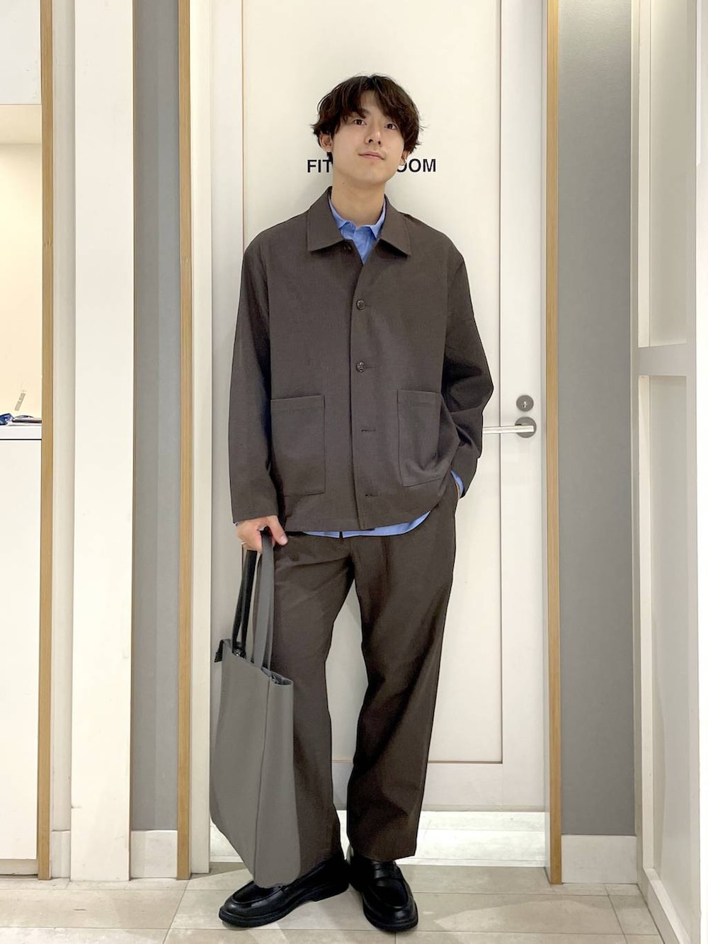 グレー系のトートバッグ、グレー系のその他シューズ、ブルー系のシャツ/ブラウスを着用したメンズの秋コーディネートの2枚目の写真