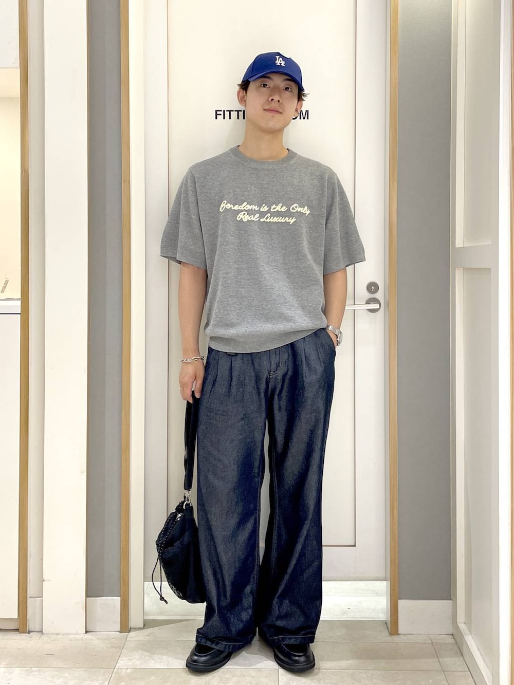 ブラック系のショルダーバッグ、グレー系のニット/セーター、ブルー系のデニムパンツを着用したメンズの夏コーディネートの3枚目の写真