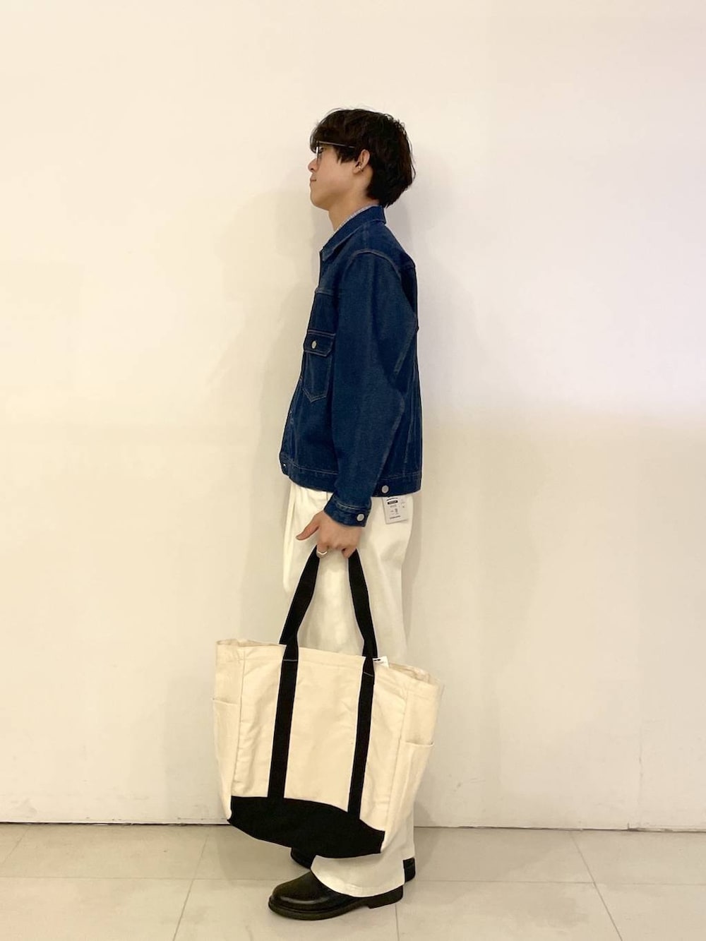 ホワイト系のトートバッグ、ブルー系のデニムジャケット、ホワイト系のその他パンツを着用したメンズの春コーディネートの2枚目の写真