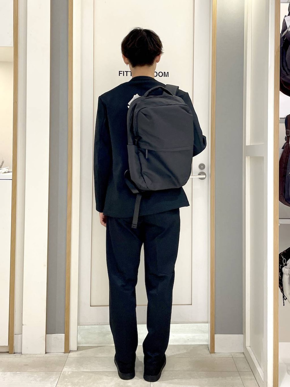 ブラック系のスニーカー、グレー系のバックパック/リュック、ブルー系のその他パンツを着用したメンズの秋コーディネートの5枚目の写真