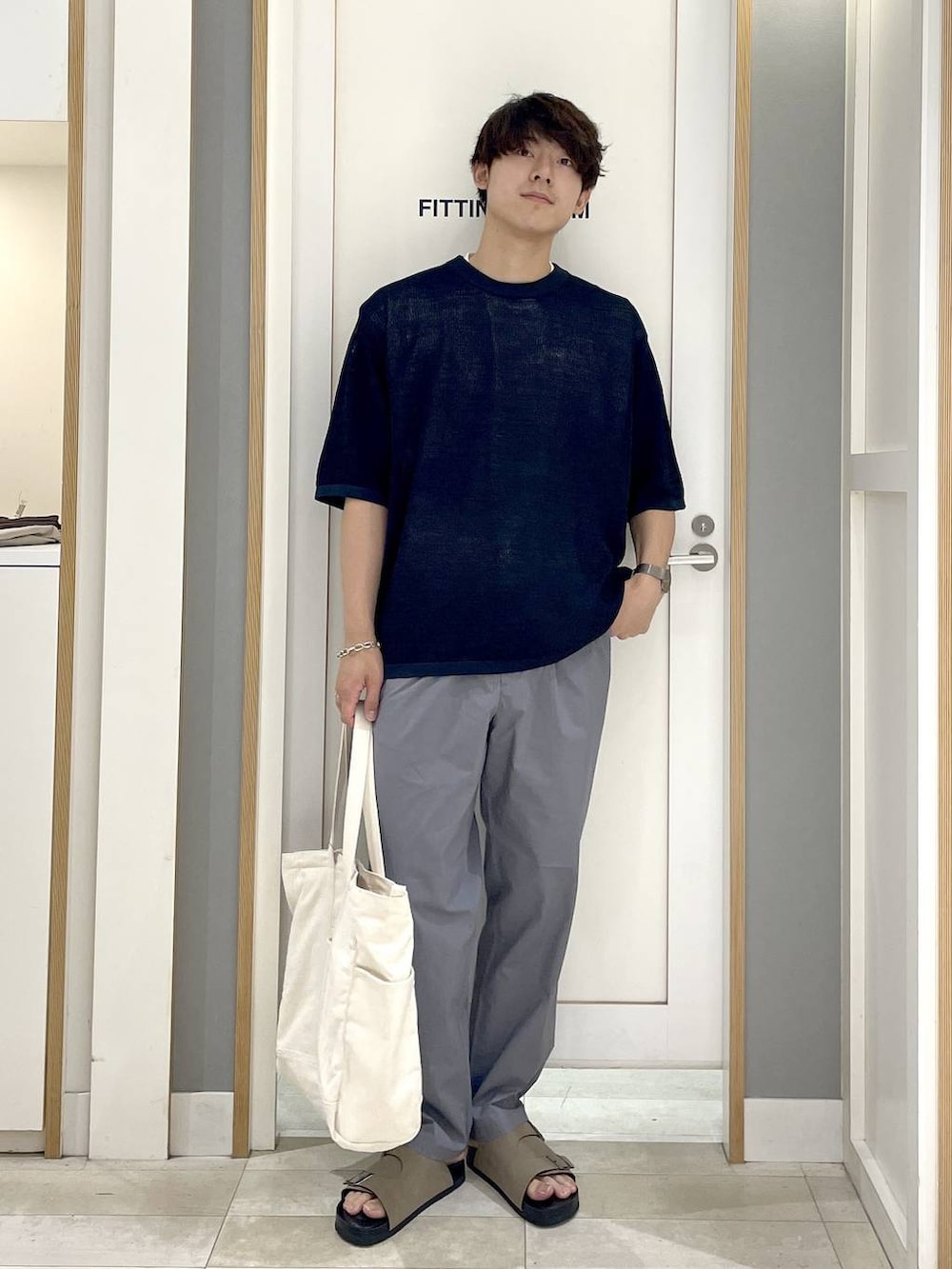ブルー系のニット/セーター、ホワイト系のトートバッグ、グレー系のその他パンツを着用したメンズの秋コーディネートの2枚目の写真