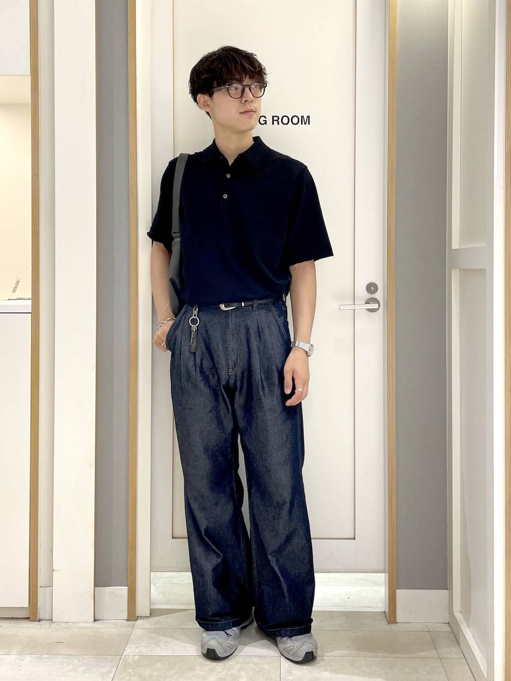 グレー系のショルダーバッグ、ブラック系のポロシャツ、ブルー系のデニムパンツを着用したメンズの秋コーディネートの4枚目の写真