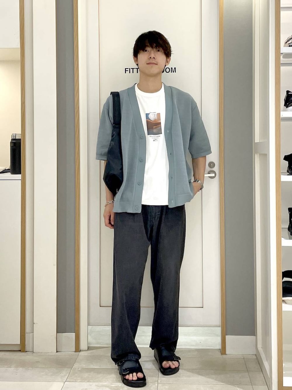 ブラック系のショルダーバッグ、ホワイト系のTシャツ/カットソー、グレー系のデニムパンツを着用したメンズの夏コーディネートの4枚目の写真