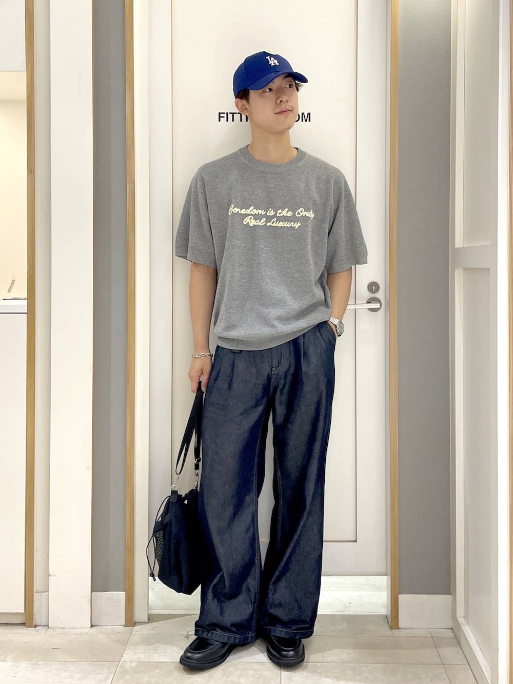ブラック系のショルダーバッグ、グレー系のニット/セーター、ブルー系のデニムパンツを着用したメンズの夏コーディネートの2枚目の写真