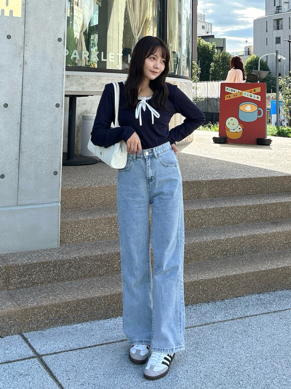 ホワイト系のバッグ、ブルー系のデニムパンツ、ホワイト系のスニーカーを着用したレディースの秋コーディネートの4枚目の写真