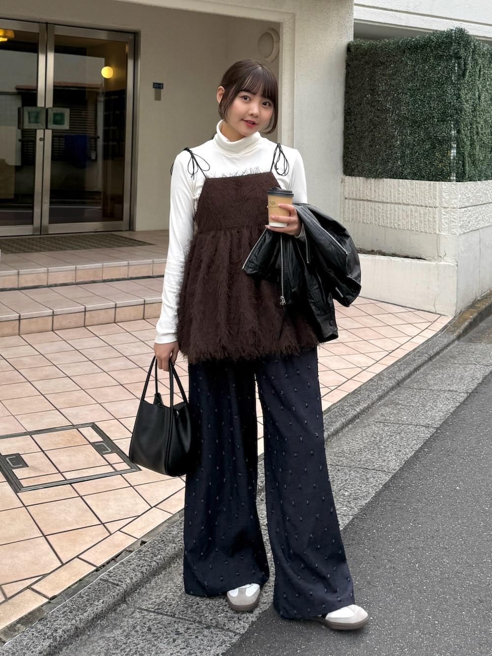 ブラウン系のキャミソール、ホワイト系のニット/セーター、ブラック系のブルゾンを着用したレディースの秋コーディネートの4枚目の写真