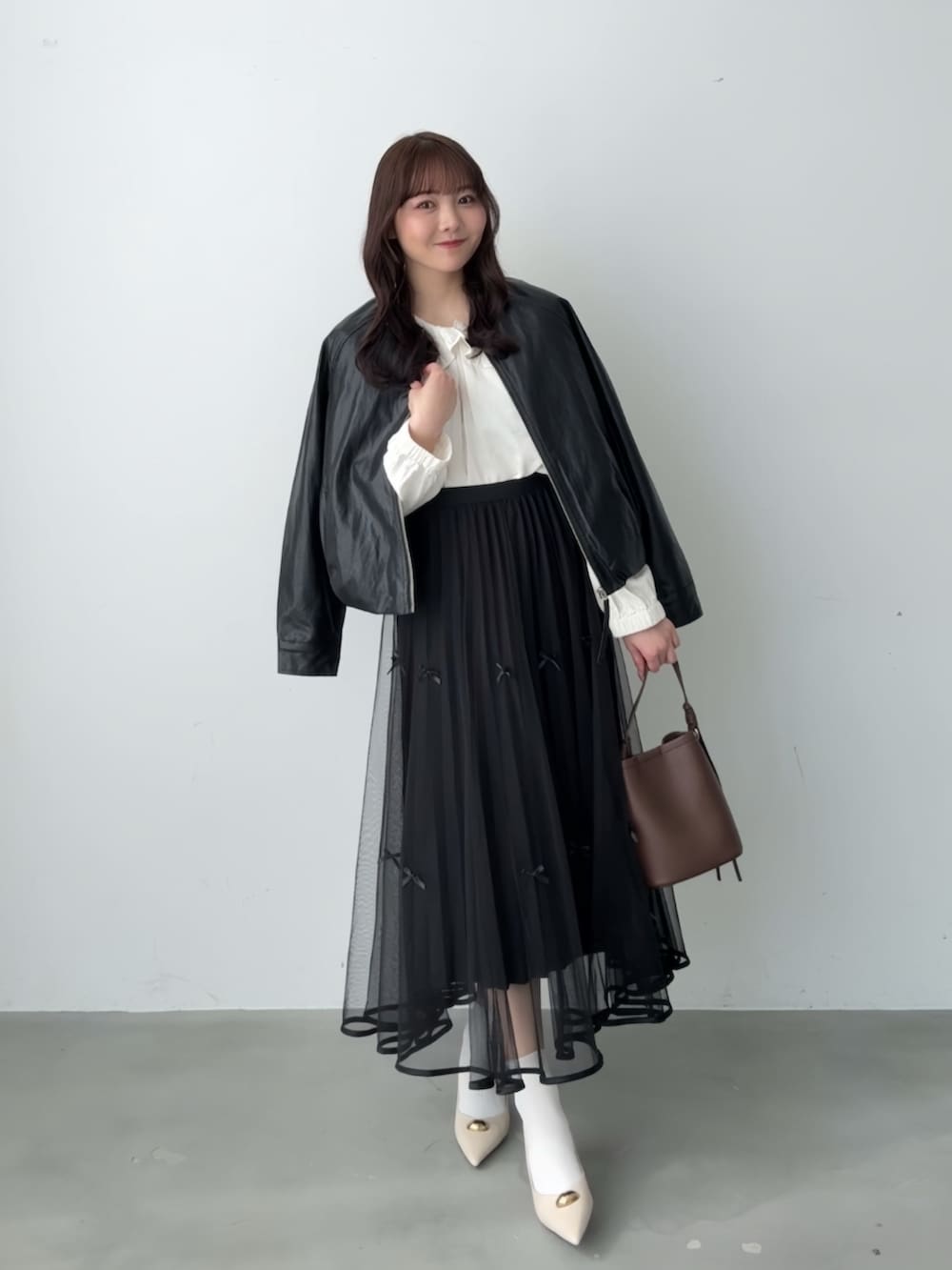 ホワイト系のシャツ/ブラウス、ブラック系のスカート、ブラウン系のハンドバッグを着用したレディースの春コーディネートの4枚目の写真