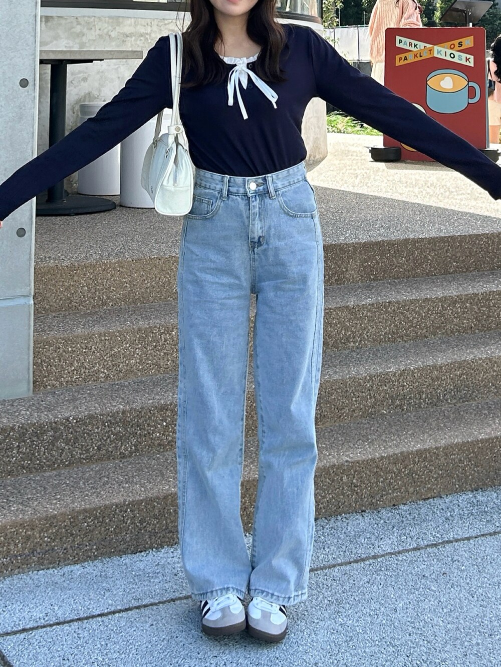 ホワイト系のバッグ、ブルー系のデニムパンツ、ホワイト系のスニーカーを着用したレディースの秋コーディネートの2枚目の写真