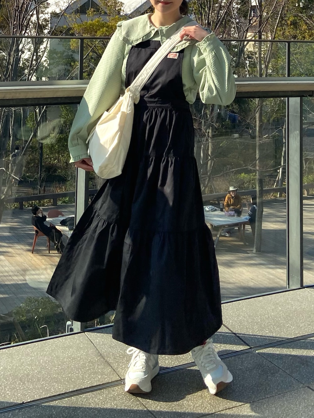 ブラック系のワンピース、ベージュ系のショルダーバッグ、グリーン系のシャツ/ブラウスを着用したレディースの春コーディネートの2枚目の写真