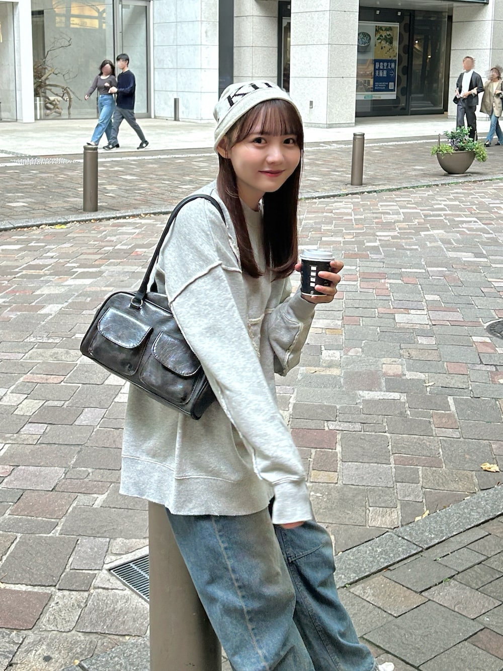 グレー系のスウェット、ブラック系のバッグ、ブルー系のデニムパンツを着用したレディースの秋コーディネートの3枚目の写真