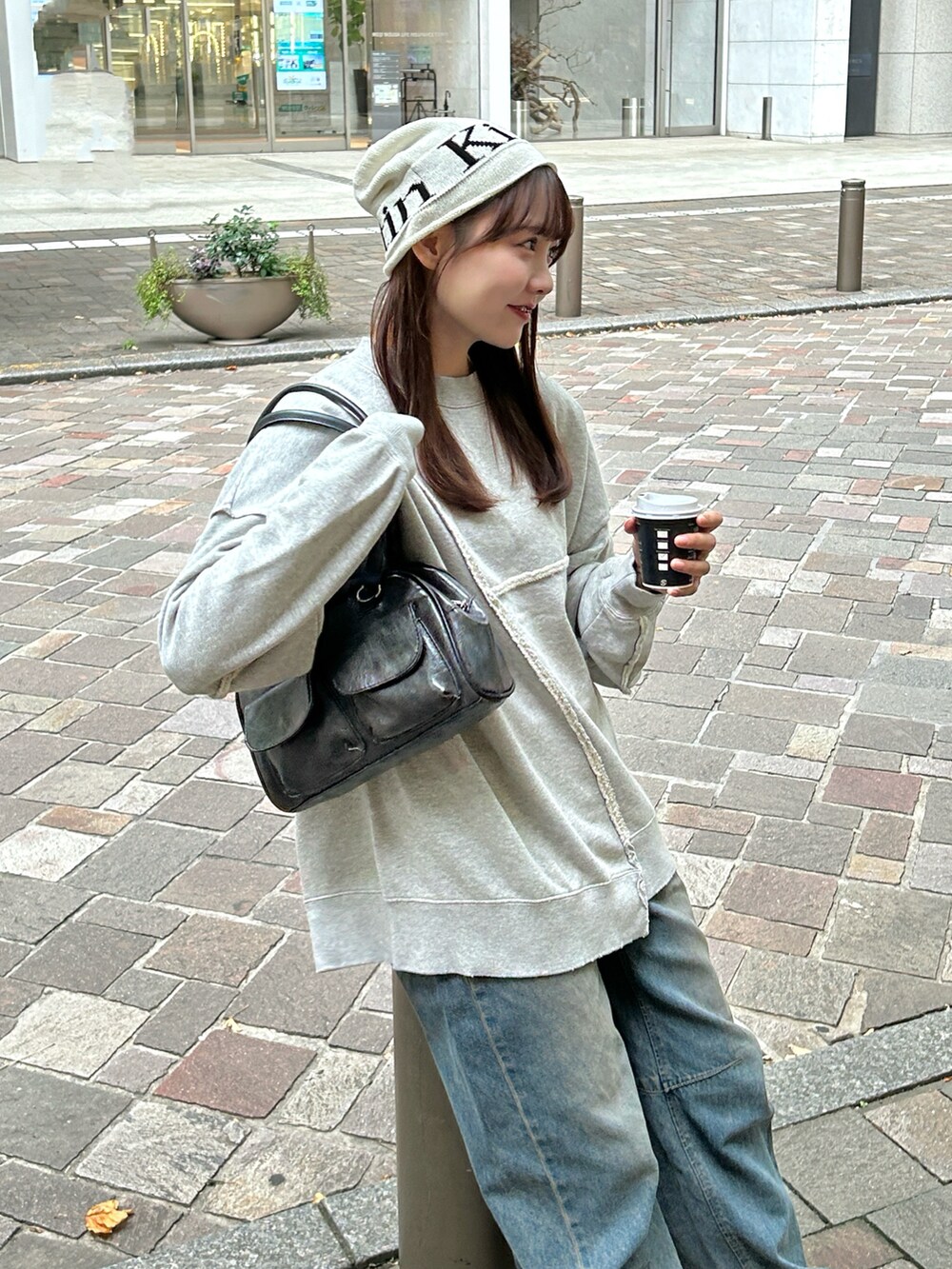 グレー系のスウェット、ブラック系のバッグ、ブルー系のデニムパンツを着用したレディースの秋コーディネートの2枚目の写真