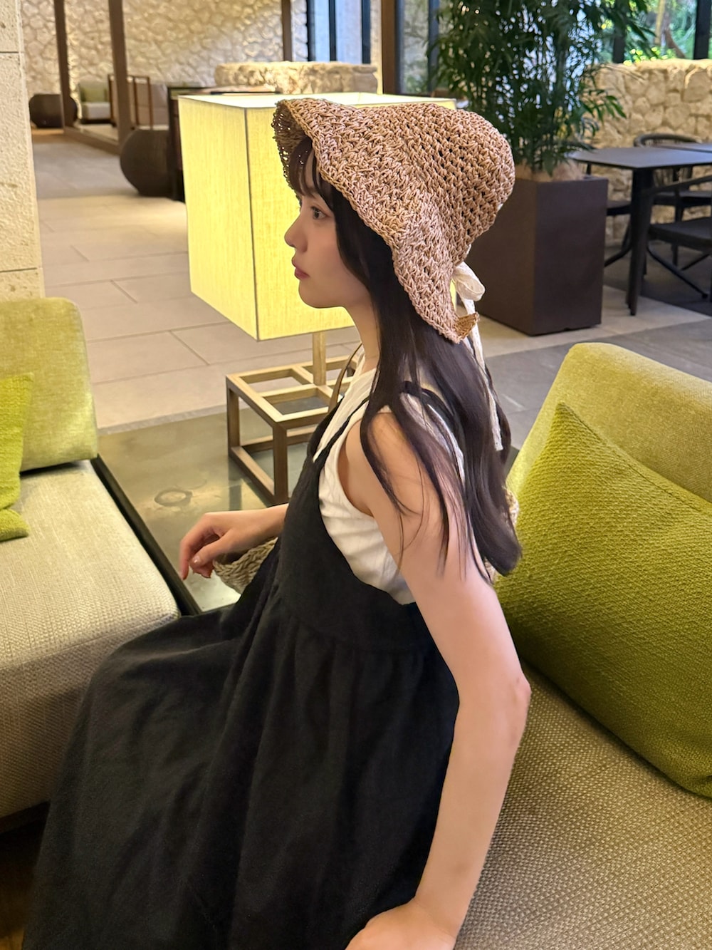 ブラウン系のパンプス、ブラック系のワンピース、ホワイト系のかごバッグを着用したレディースの夏コーディネートの3枚目の写真