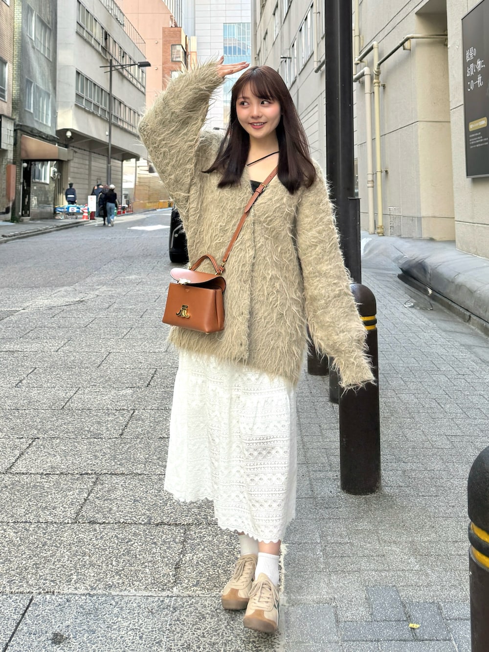 ベージュ系のタンクトップ、グリーン系のカーディガン/ボレロ、ホワイト系のスカートを着用したレディースの春コーディネートの2枚目の写真