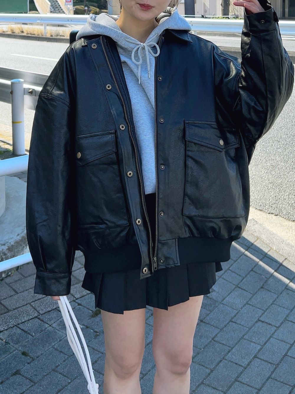 グレー系のパーカー、ブラック系のブルゾン、ブラック系のスカートを着用したレディースの冬コーディネートの3枚目の写真