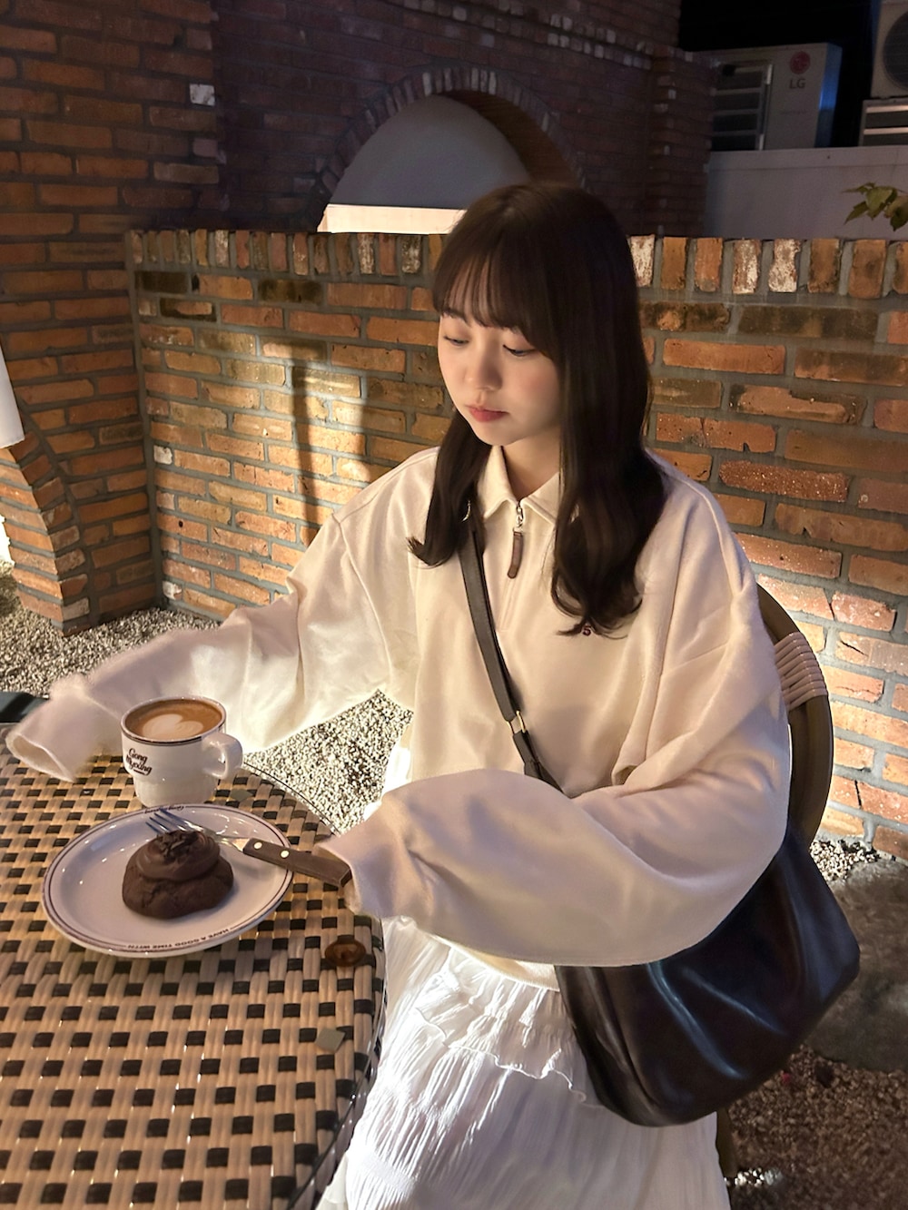 ブラウン系のショルダーバッグ、ホワイト系のスウェット、ホワイト系のワンピースを着用したレディースの秋コーディネートの2枚目の写真