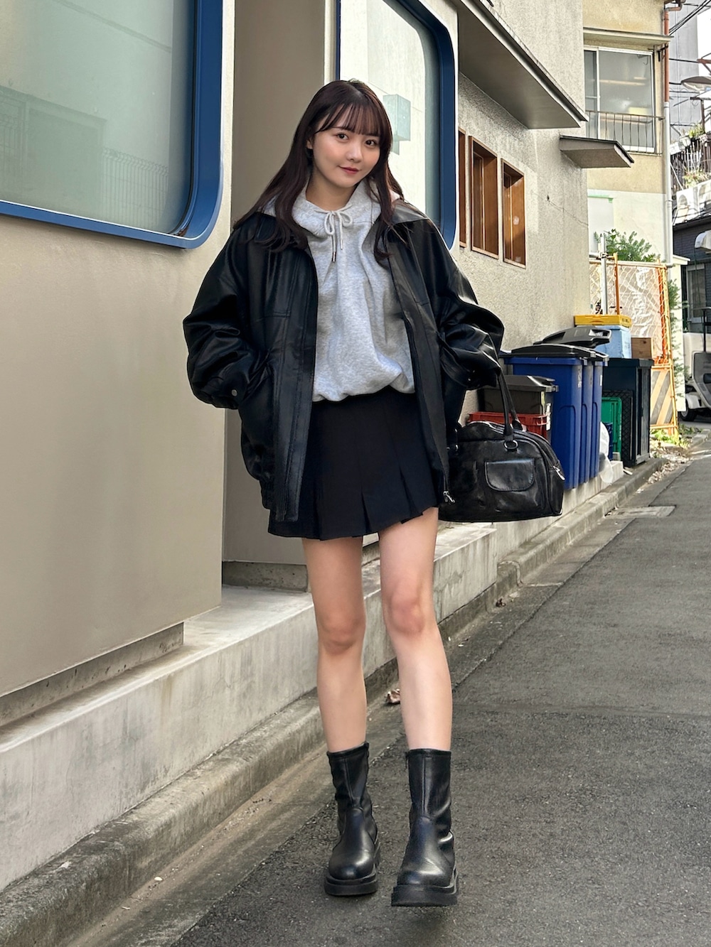 グレー系のパーカー、ブラック系のブルゾン、ブラック系のスカートを着用したレディースの秋コーディネートの2枚目の写真