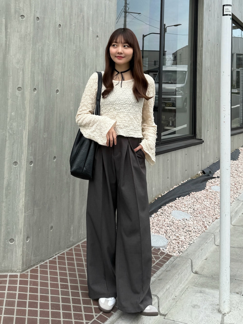 ブラック系のバッグ、ホワイト系のTシャツ/カットソー、グレー系のスラックスを着用したレディースの春コーディネートの2枚目の写真