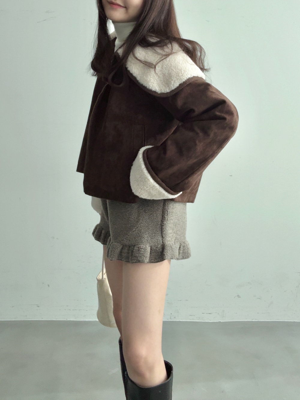 ホワイト系のショルダーバッグ、ブラック系のブーツ、グレー系のその他パンツを着用したレディースの冬コーディネートの4枚目の写真