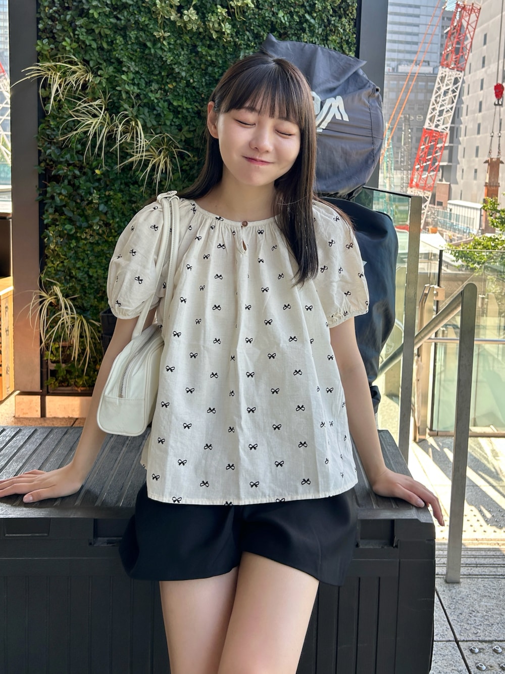 ブラック系のシャツ/ブラウス、ホワイト系のスニーカー、ホワイト系のバッグを着用したレディースの夏コーディネートの3枚目の写真