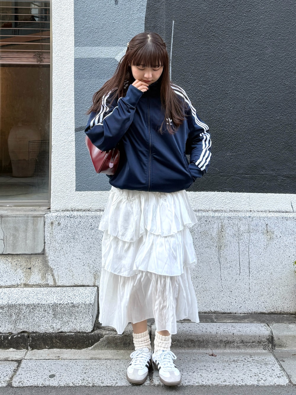 ブルー系のジャージ、レッド系のボストンバッグ、ホワイト系のスカートを着用したレディースの冬コーディネートの3枚目の写真