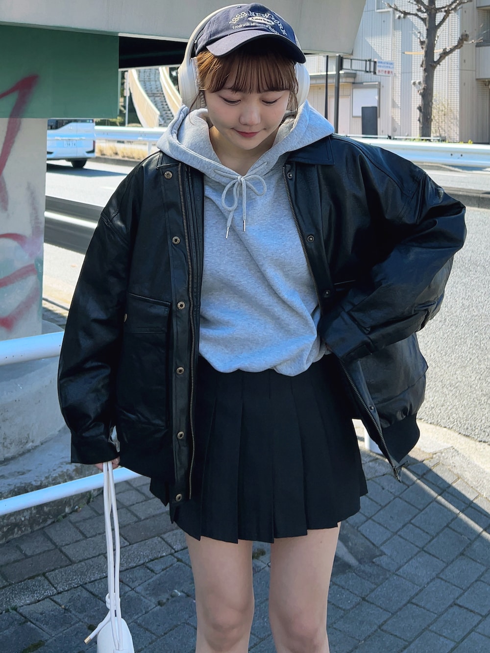 グレー系のパーカー、ブラック系のブルゾン、ブラック系のスカートを着用したレディースの冬コーディネートの4枚目の写真