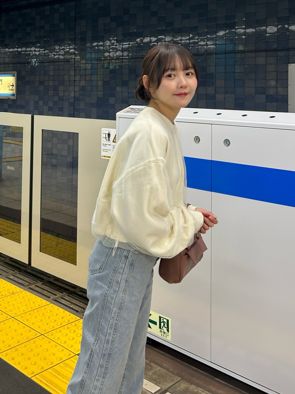 ピンク系のボストンバッグ、ブルー系のデニムパンツ、ベージュ系のステンカラーコートを着用したレディースの冬コーディネートの2枚目の写真