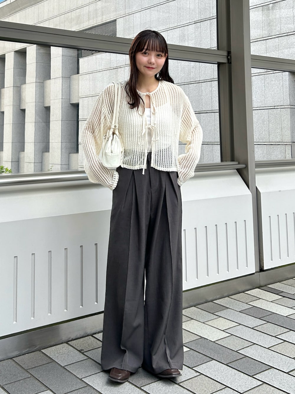 ベージュ系のカーディガン/ボレロ、グレー系のスラックス、ホワイト系のバッグを着用したレディースの秋コーディネートの2枚目の写真