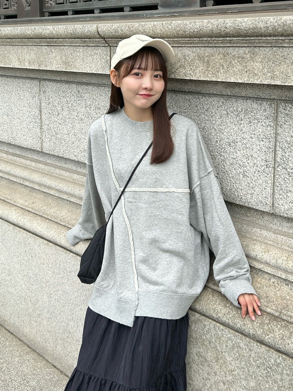 グレー系のスウェット、ブラック系のバッグ、ブラック系のスカートを着用したレディースの秋コーディネートの2枚目の写真