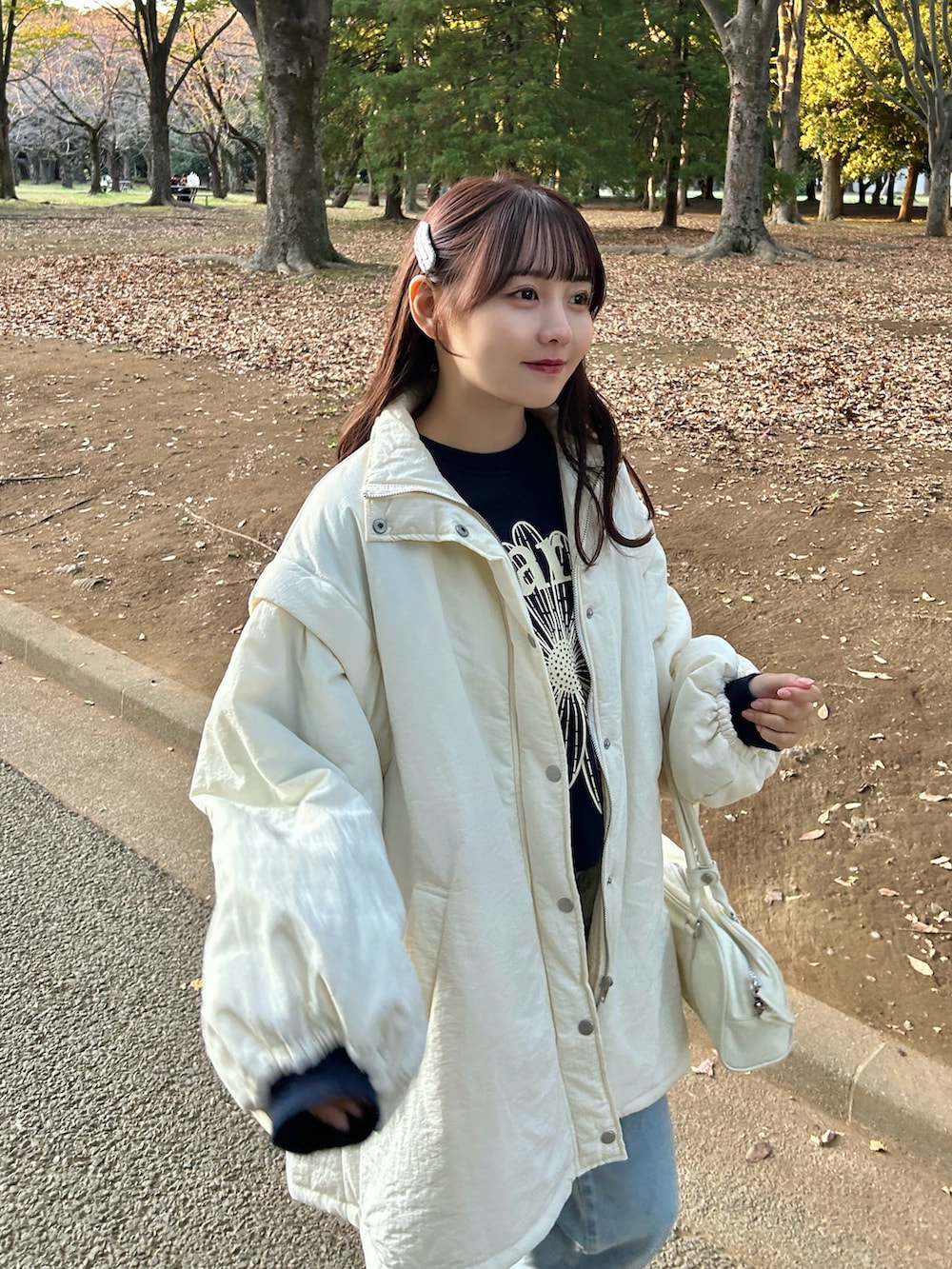 ホワイト系のダウンジャケット/コート、ブルー系のスウェット、ホワイト系のバッグを着用したレディースの冬コーディネートの3枚目の写真