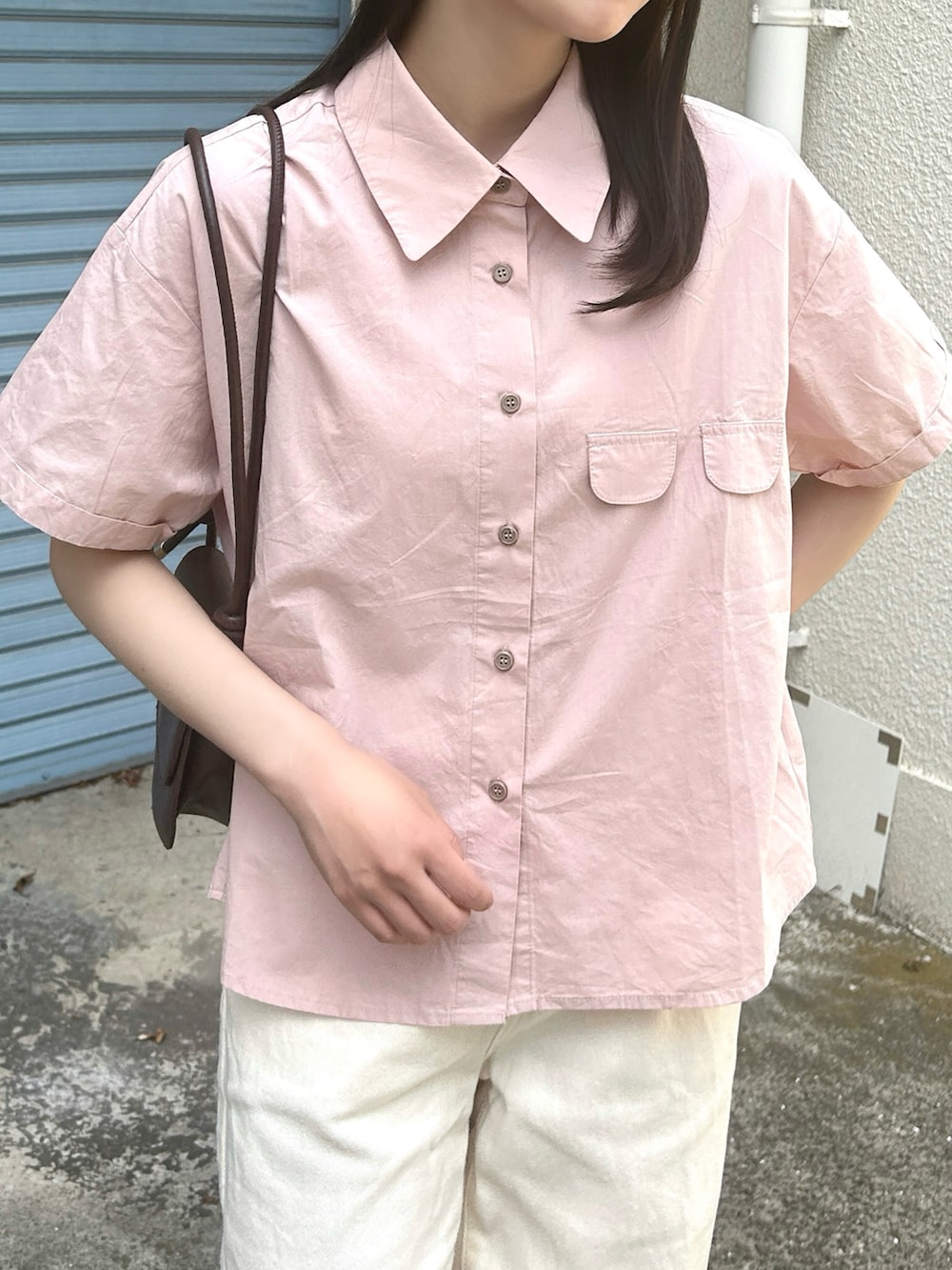 ピンク系のシャツ/ブラウス、ブラウン系のハンドバッグ、ホワイト系のパンツを着用したレディースの夏コーディネートの3枚目の写真