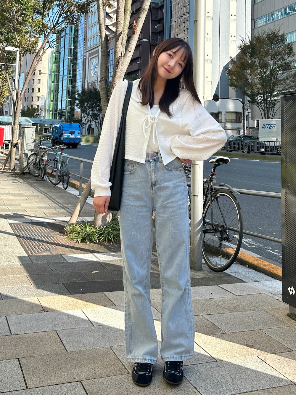 ブルー系のデニムパンツ、ブラック系のバッグ、ホワイト系のカーディガン/ボレロを着用したレディースの冬コーディネートの5枚目の写真