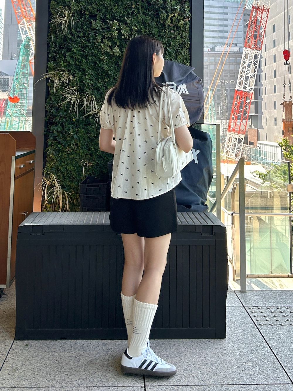 ブラック系のシャツ/ブラウス、ホワイト系のスニーカー、ホワイト系のバッグを着用したレディースの夏コーディネートの2枚目の写真