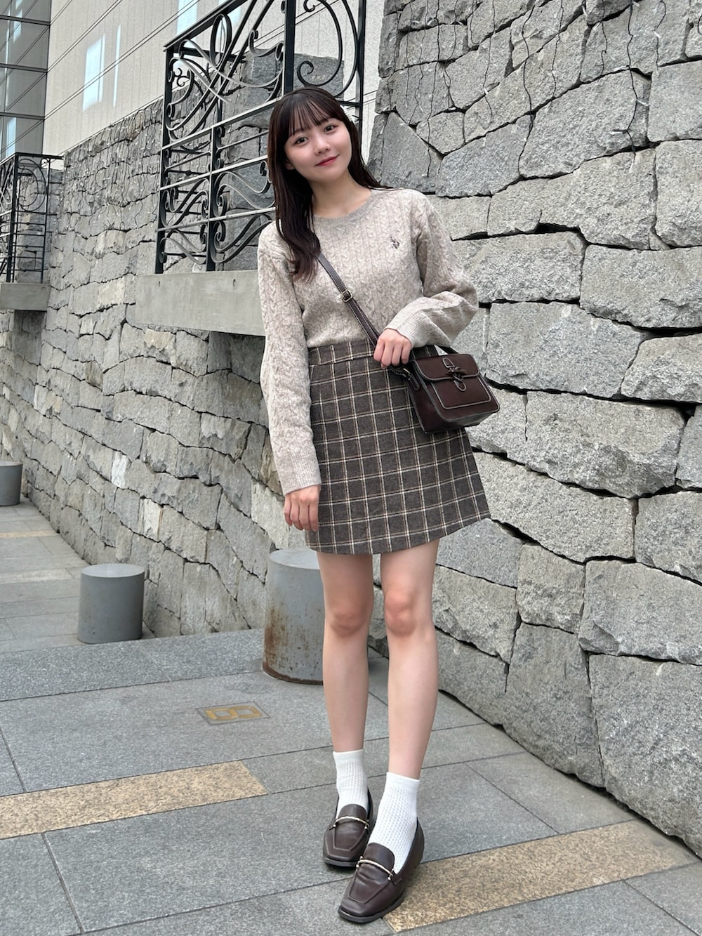 ベージュ系のニット/セーター、ブラウン系のショルダーバッグ、ブラウン系のスカートを着用したレディースの秋コーディネートの3枚目の写真