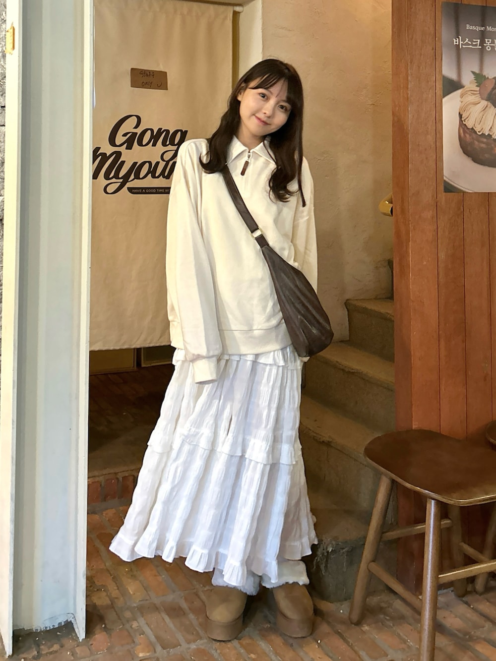 ブラウン系のショルダーバッグ、ホワイト系のスウェット、ホワイト系のワンピースを着用したレディースの秋コーディネートの3枚目の写真