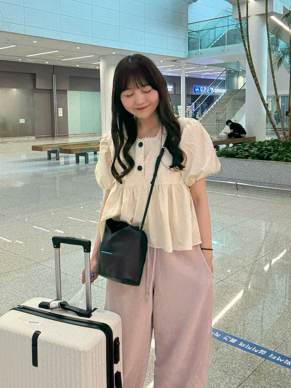 ベージュ系のシャツ/ブラウス、ブラック系のショルダーバッグ、ブルー系のデニムパンツを着用したレディースの春コーディネートの3枚目の写真