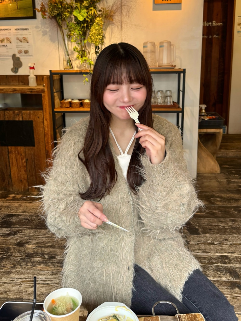 ブラック系のデニムパンツ、グリーン系のカーディガン/ボレロ、ベージュ系のタンクトップを着用したレディースの秋コーディネートの4枚目の写真