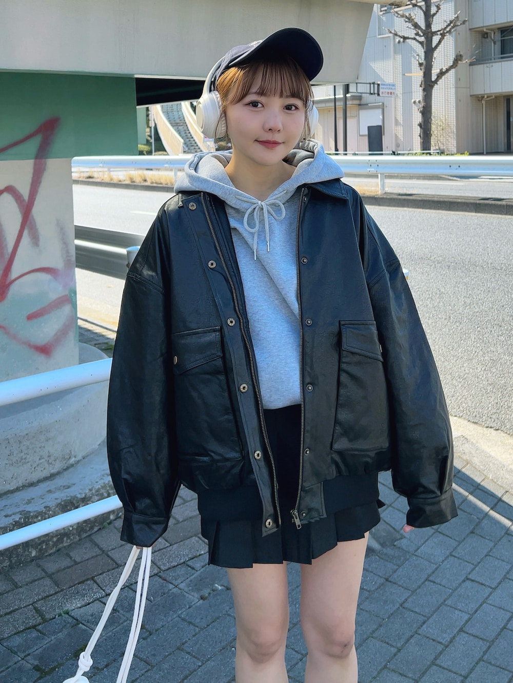 グレー系のパーカー、ブラック系のブルゾン、ブラック系のスカートを着用したレディースの冬コーディネートの5枚目の写真