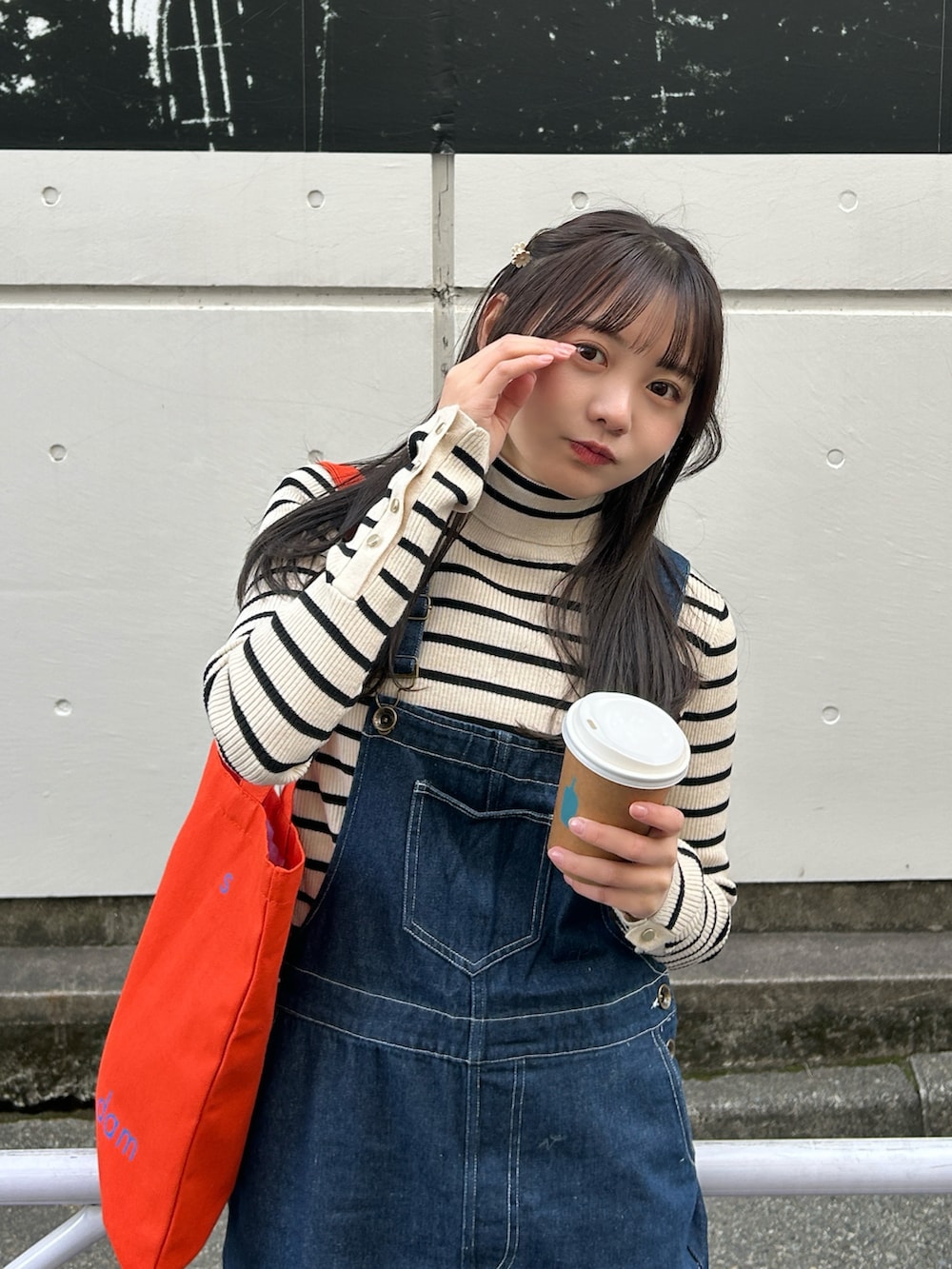 ブラック系のステンカラーコート、ホワイト系のニット/セーター、ブルー系のサロペット/オーバーオールを着用したレディースの冬コーディネートの4枚目の写真