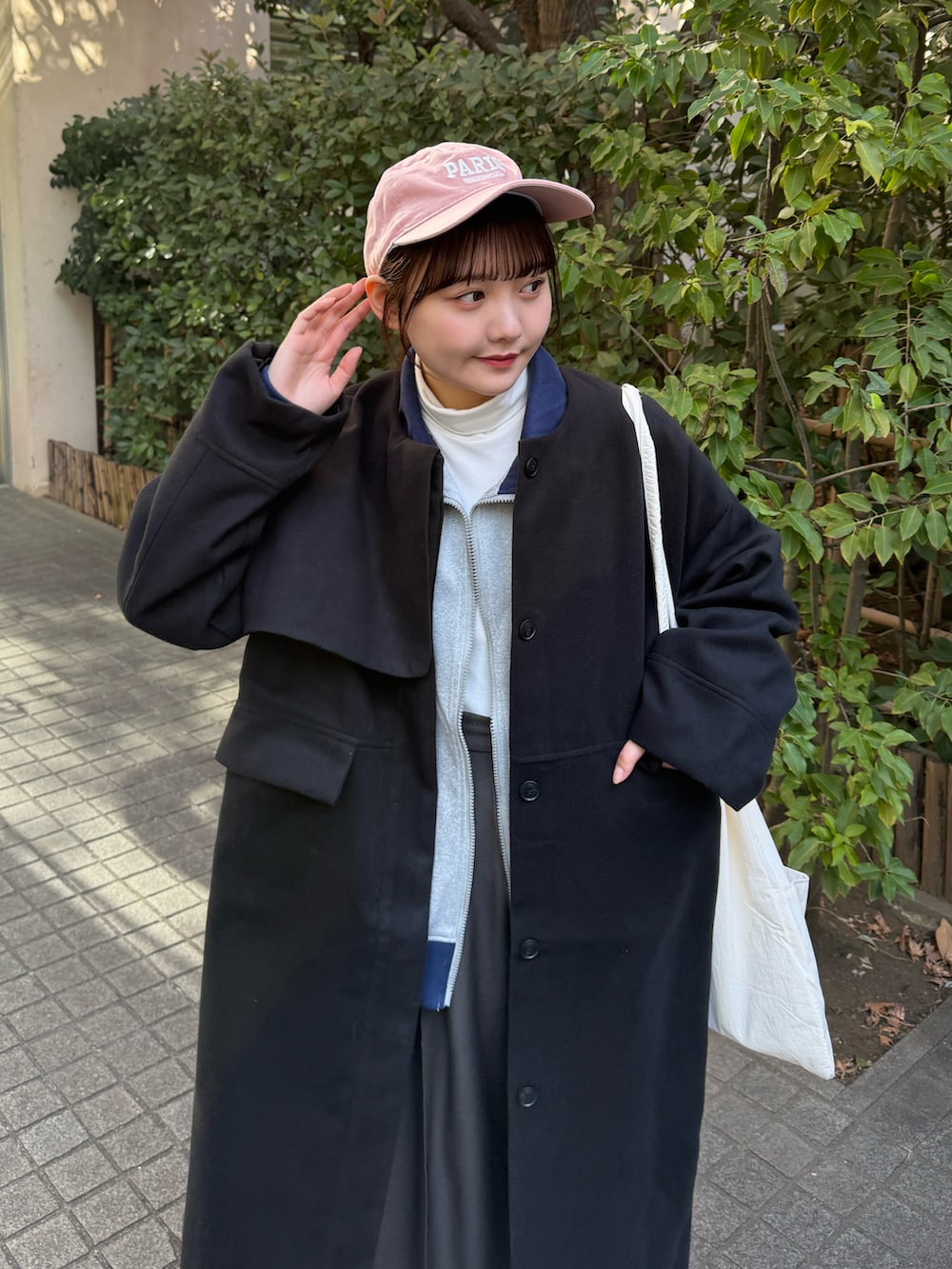 グレー系のブルゾン、ホワイト系のトップス、グレー系のスラックスを着用したレディースの冬コーディネートの2枚目の写真