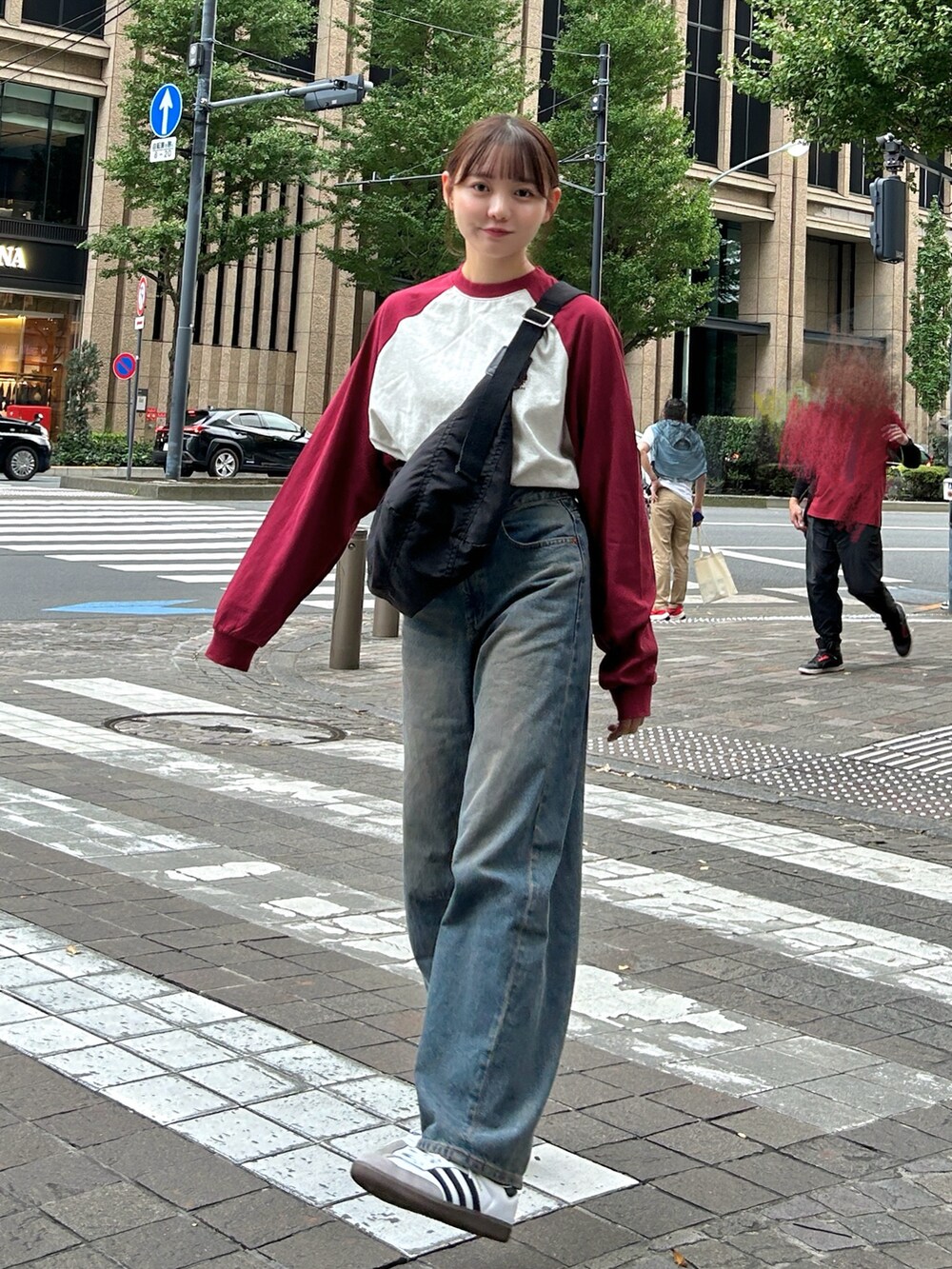 レッド系のTシャツ/カットソー、ブラック系のショルダーバッグ、ブルー系のデニムパンツを着用したレディースの秋コーディネートの4枚目の写真
