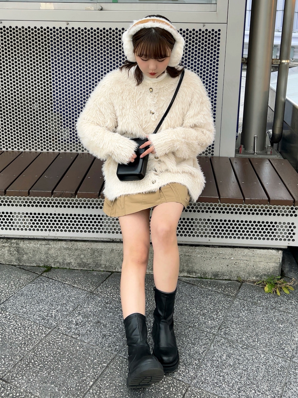 ブラック系のブーツ、ベージュ系のスカート、ブラック系のショルダーバッグを着用したレディースの冬コーディネートの3枚目の写真