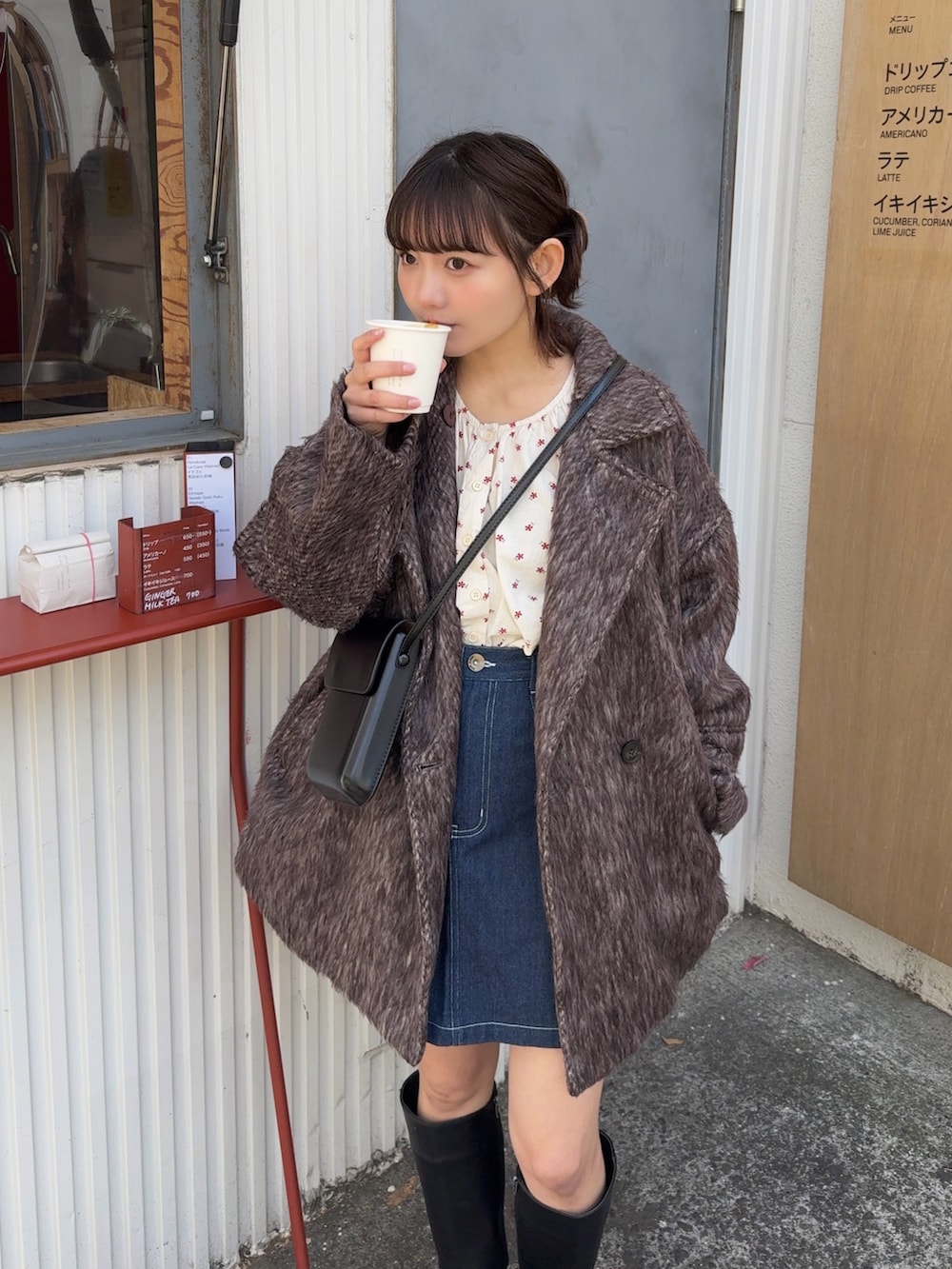 ブラウン系のピーコート、ブラック系のショルダーバッグ、ブラック系のブーツを着用したレディースの冬コーディネートの3枚目の写真