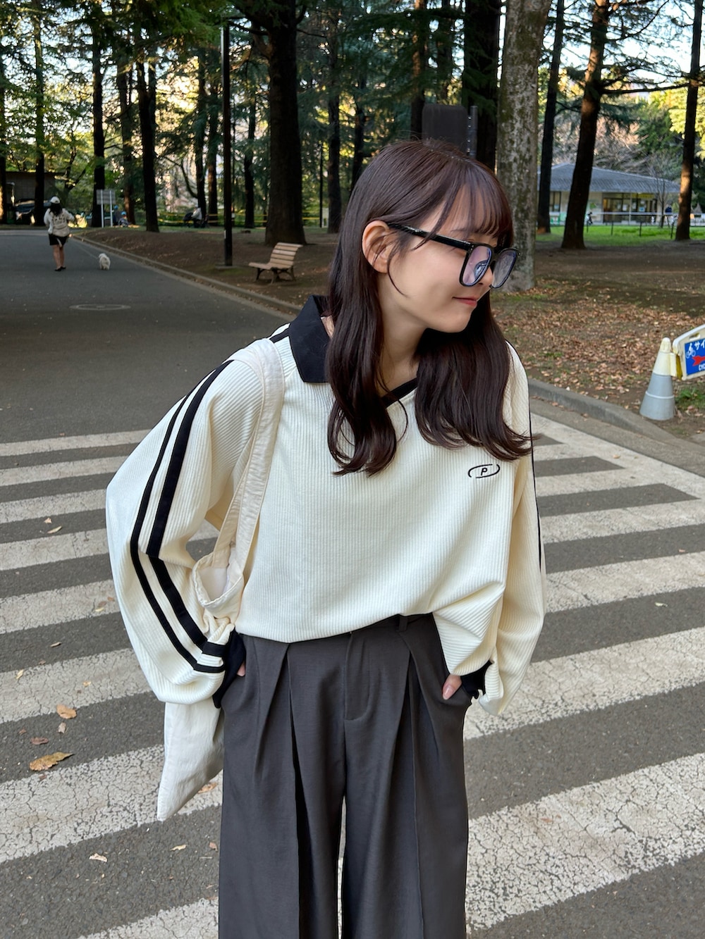 ホワイト系のスウェット、ホワイト系のトートバッグ、グレー系のスラックスを着用したレディースの冬コーディネートの3枚目の写真