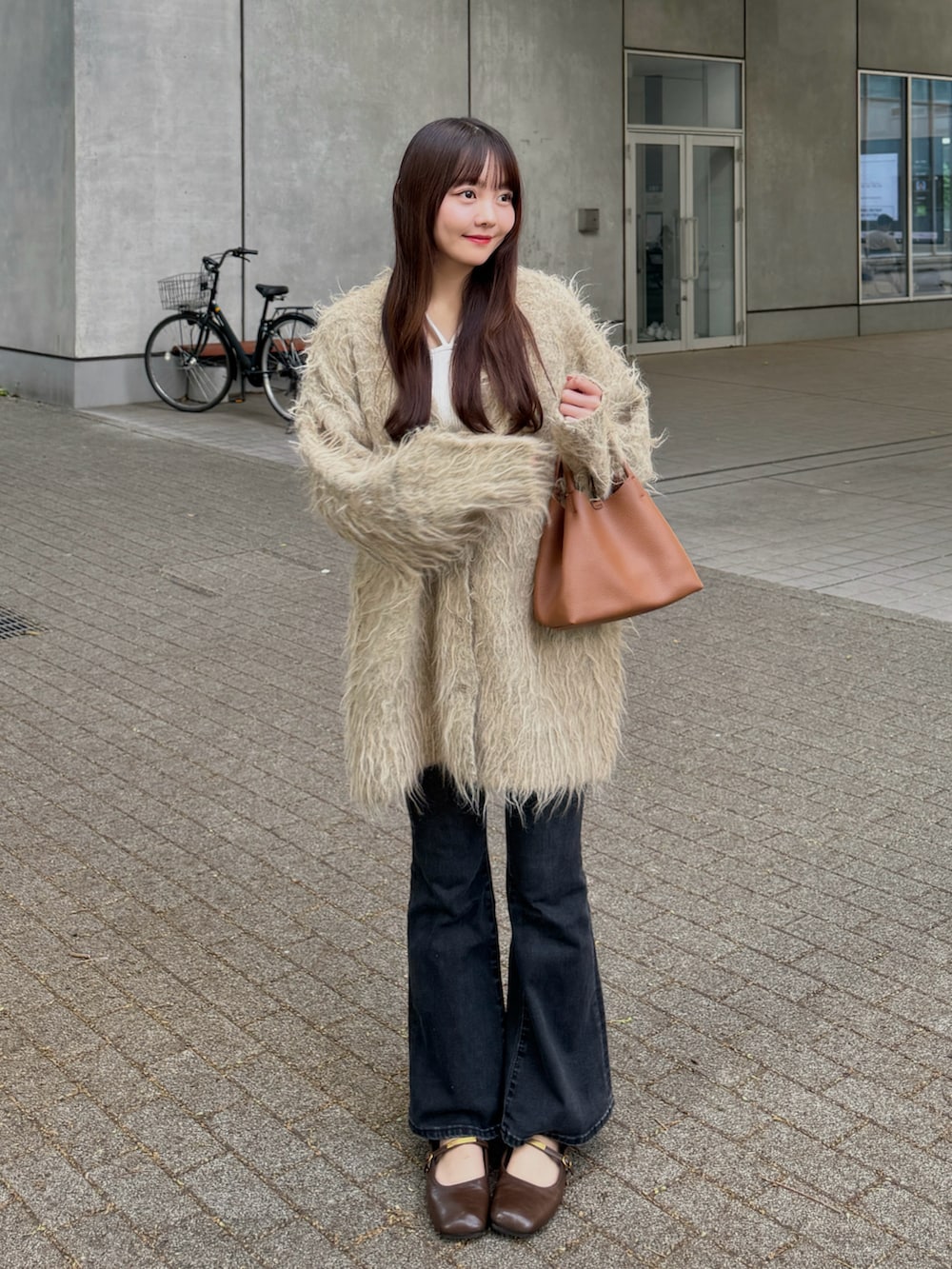 ブラック系のデニムパンツ、グリーン系のカーディガン/ボレロ、ベージュ系のタンクトップを着用したレディースの秋コーディネートの2枚目の写真