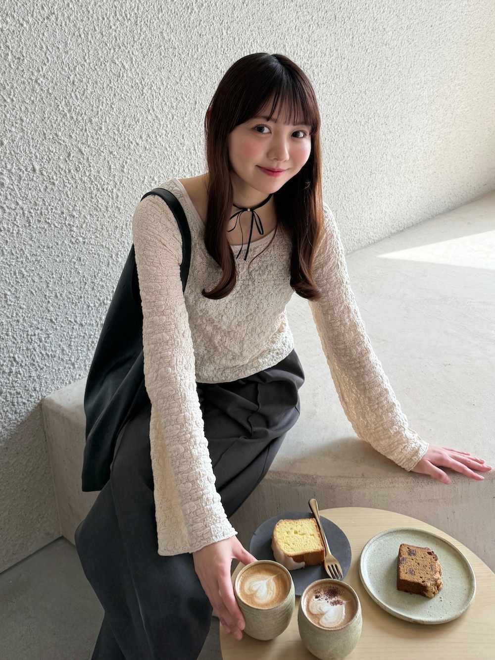 ブラック系のバッグ、ホワイト系のTシャツ/カットソー、グレー系のスラックスを着用したレディースの春コーディネートの5枚目の写真