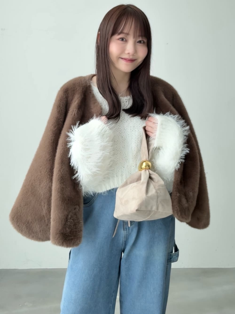 ホワイト系のニット/セーター、ブラウン系のブルゾン、ブルー系のデニムパンツを着用したレディースの春コーディネートの2枚目の写真