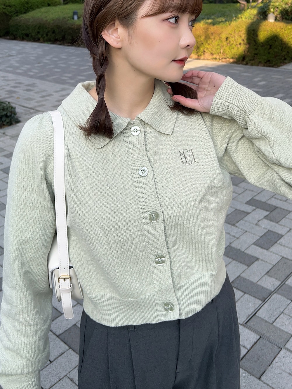 グリーン系のニット/セーター、ホワイト系のハンドバッグ、グレー系のパンツを着用したレディースの春コーディネートの4枚目の写真