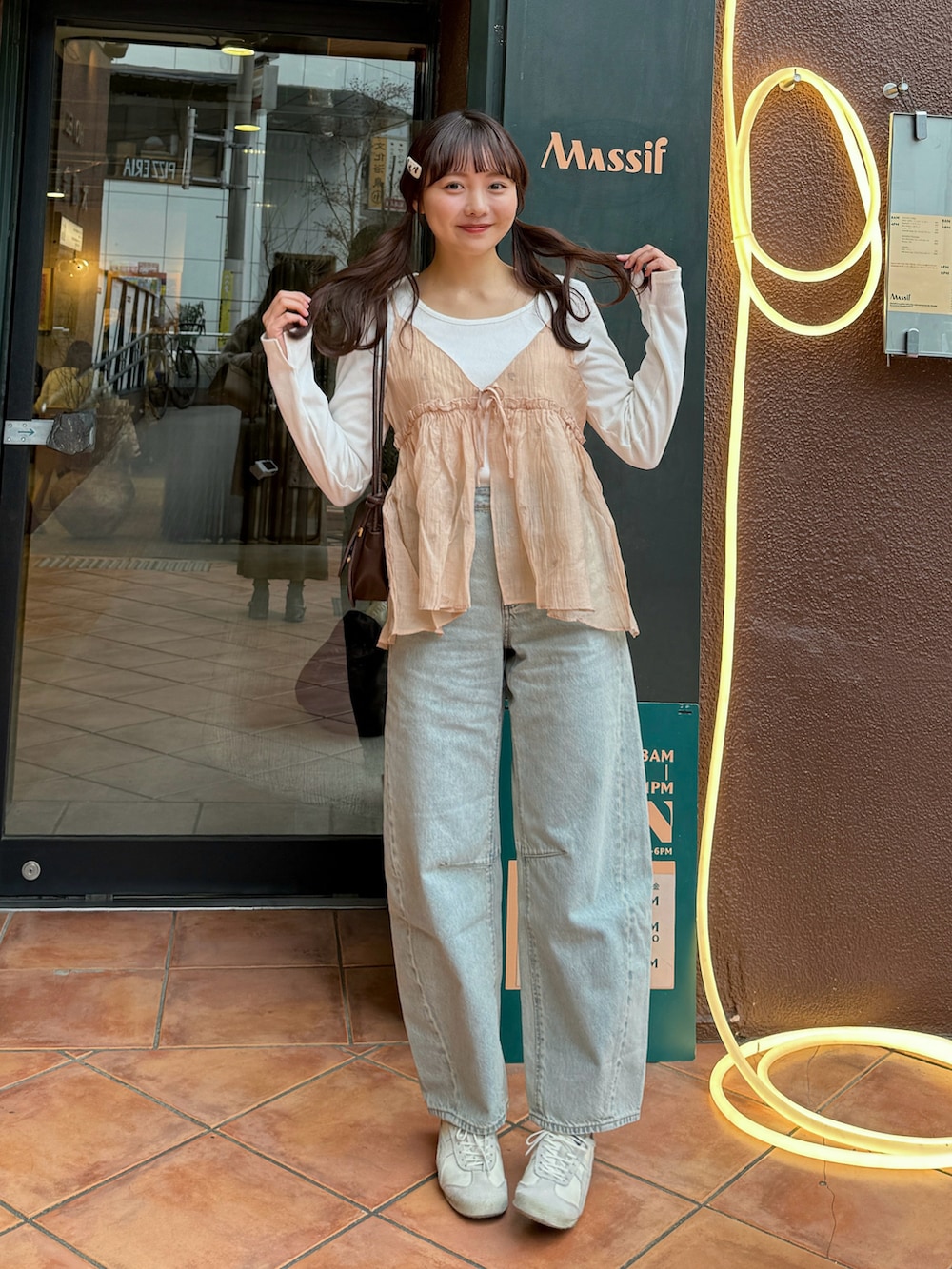 ピンク系のキャミソール、ホワイト系のトップス、ブルー系のデニムパンツを着用したレディースの春コーディネートの2枚目の写真